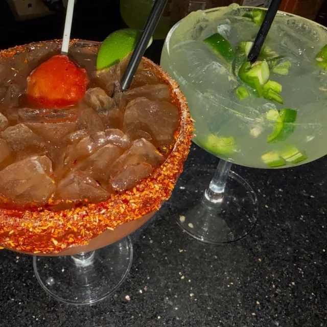 A strawberry margarita and a jalapeño margarita side by side on the bar
