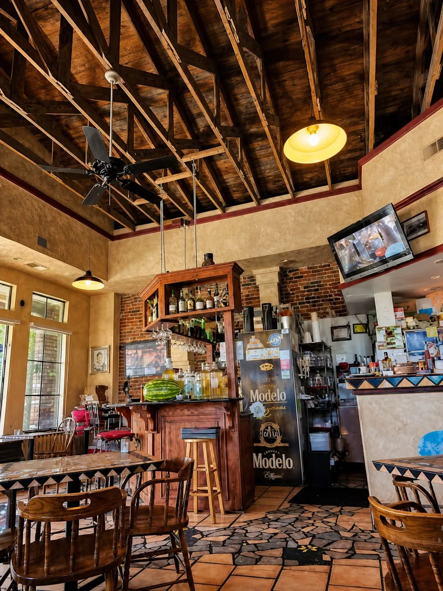 Inside El Jardín — wood-truss ceiling, warm tile floors and the little bar stocked for the evening